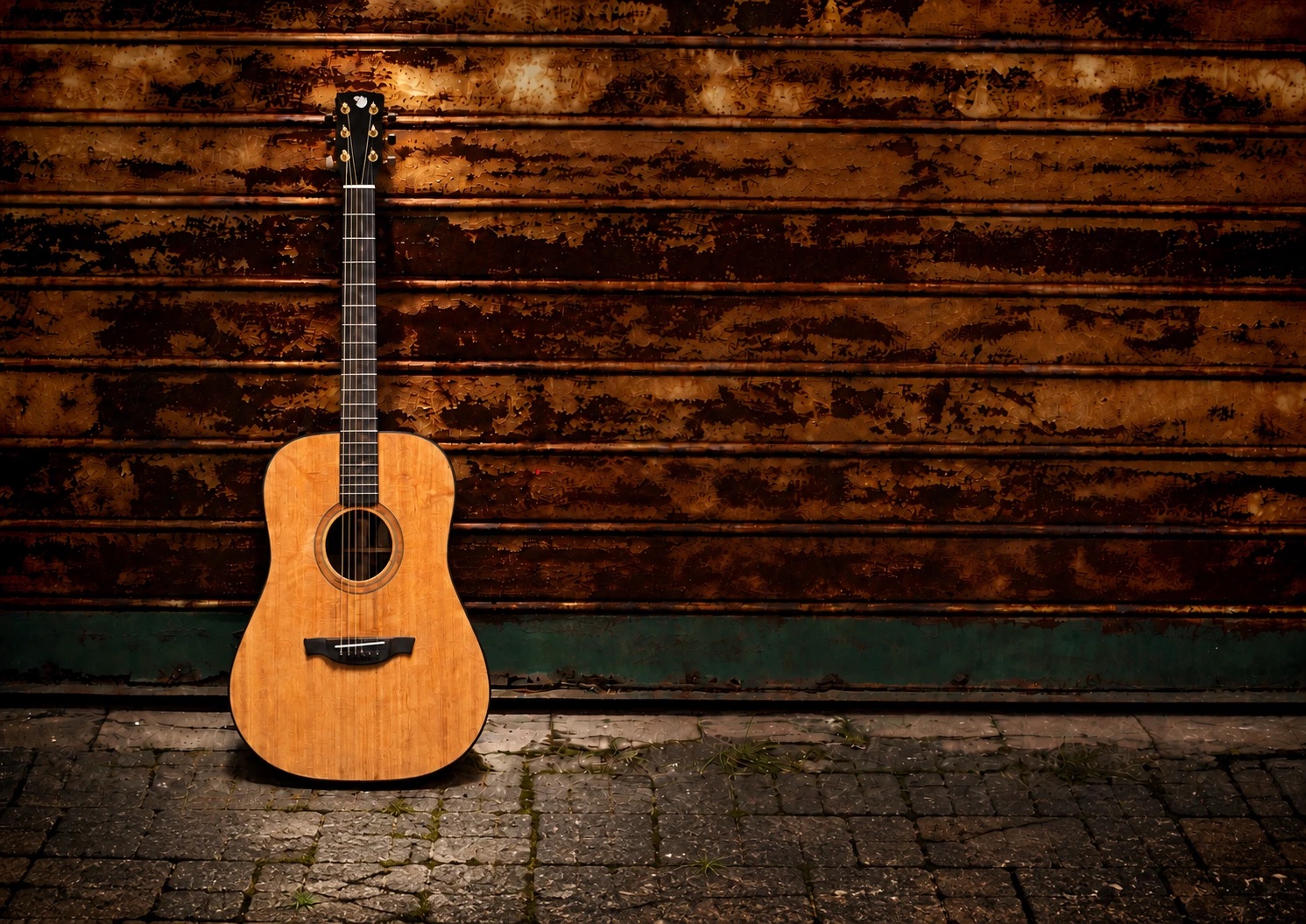 An acoustic guitar leaning against a rusted wall